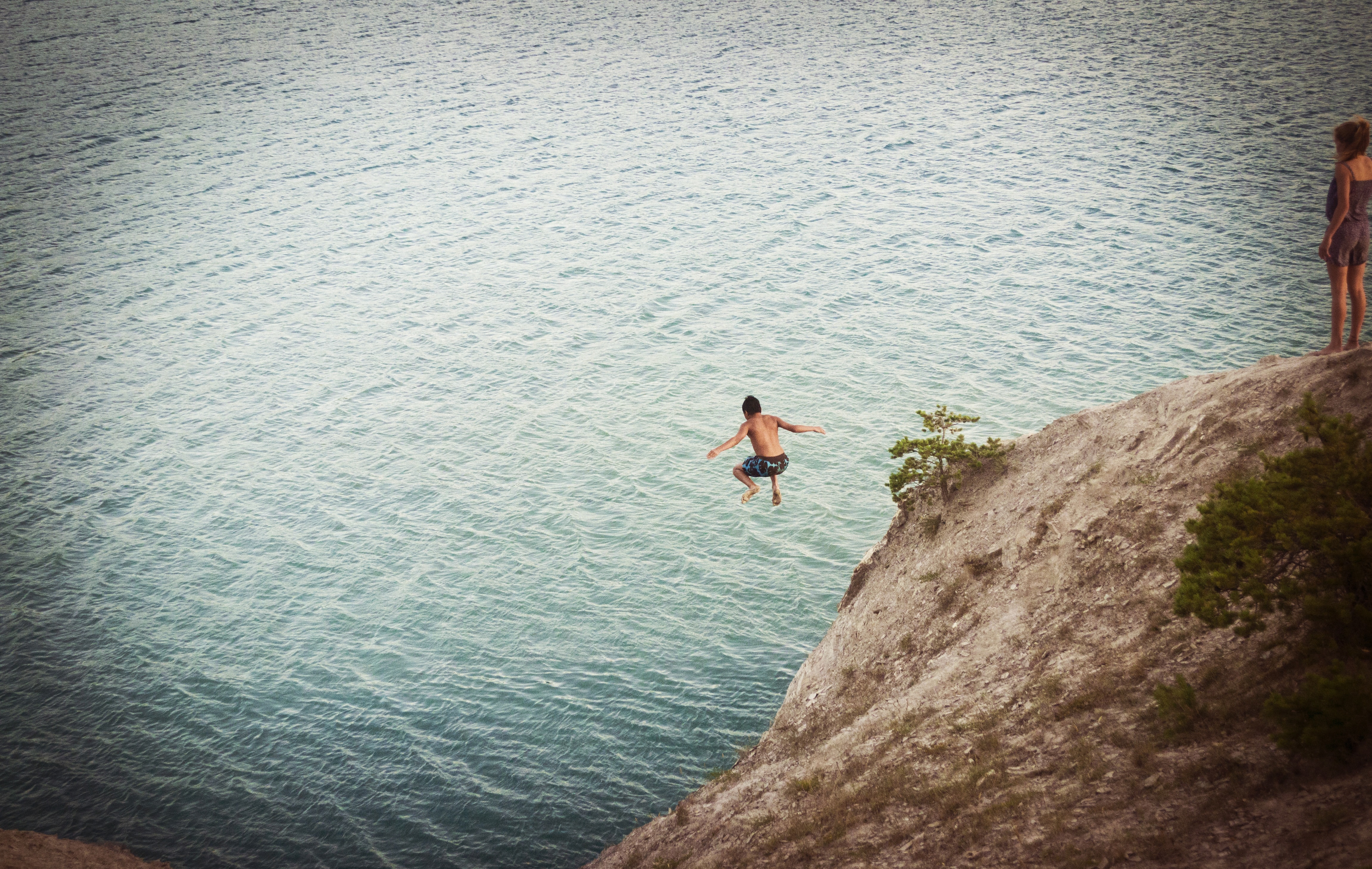 Man jumping into water from cliff